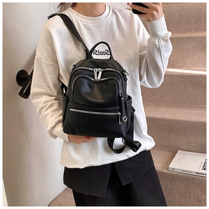Close-up of a black mini leather backpack with three zipper pockets and silver hardware