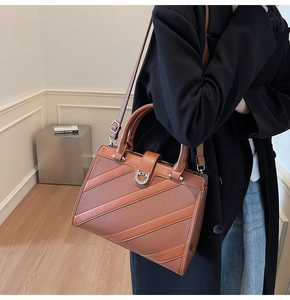 Dettaglio borsa tote in pelle marrone con fibbia a ferro di cavallo e strisce