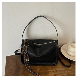 Détail d'un sac carré rétro noir avec texture grainée et breloque cacahuète en cuir