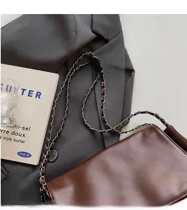 Detail of silver metal chain strap and dark brown smooth leather on a shoulder bag