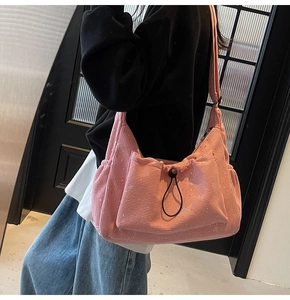 Detailed side view of pink corduroy hobo bag with drawstring pocket on a female model