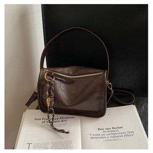 Détail macro d'un sac à bandoulière vintage marron foncé avec ferrures dorées