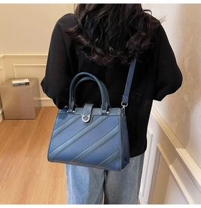 Vista dettagliata di una borsa tote in pelle blu indossata da una modella in interno