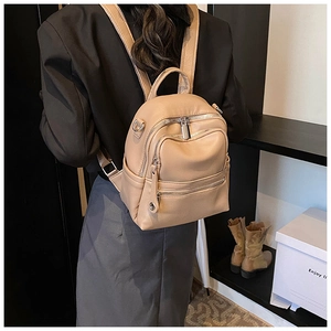 Detail view of beige faux leather mini backpack featuring multi-layer metal zippers