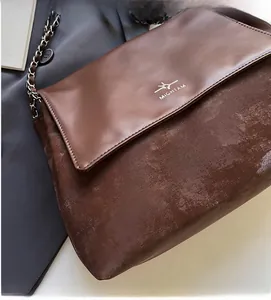 Macro detail of the vintage brown leather shoulder bag with metallic chain strap and logo