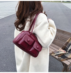 Deep red patent leather shoulder bag with dual front pockets and glossy finish detail