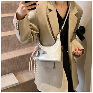Détails d'un sac hobo argenté avec boucles métalliques et pendentif en feuille