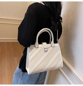 Dettaglio della borsa tote in pelle bianca con cuciture diagonali e fibbia in metallo tonda
