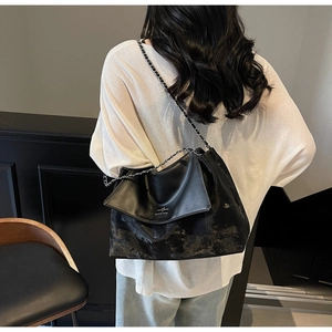 Back view of a large black chain tote bag with vintage finish on a female model
