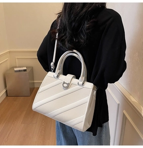 Dettaglio di una borsa bianca in pelle con fibbia a ferro di cavallo e tracolla argento