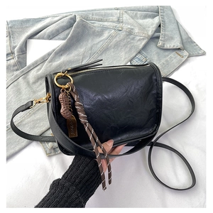 Détail du sac en cuir noir avec zip doré et pendentif original en forme d'arachide