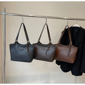 Detailansicht der Tragetaschen in Schwarz, Taupe und Dunkelbraun mit gewebtem Anhänger