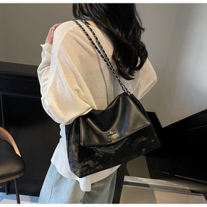 Detail of vintage black leather tote bag with silver chain strap and brand logo engraving