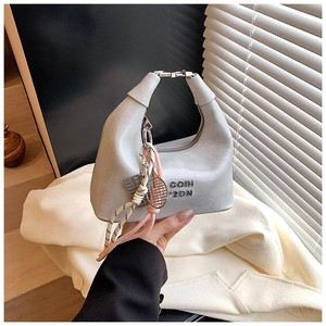Détail du sac à bandoulière gris clair mat avec poignée en métal et breloques