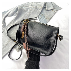 Vue détaillée du sac bandoulière noir texturé avec breloque cacahuète et dorures vintage