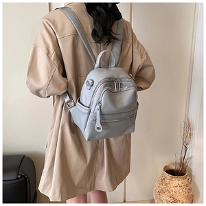 Detail view of the gray-blue backpack featuring multiple zippers and adjustable straps