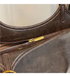 Dettaglio della cerniera dorata e trama della pelle marrone sulla borsa shopping