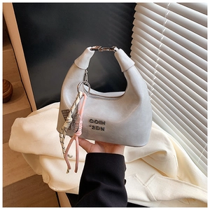 Détail d'un sac à bandoulière argenté brillant avec logo en métal et breloque tennis
