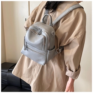 Close-up of grey mini backpack in lychee-pattern faux leather with multiple zip pockets