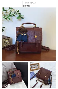 Detail view of burgundy crocodile-embossed bag with bear charm and brand logo