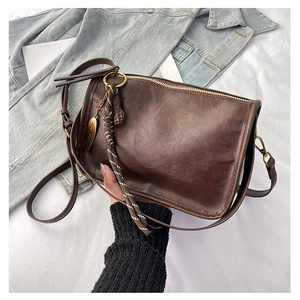 Détail du sac bandoulière marron foncé avec texture rétro huilée et pendentif doré