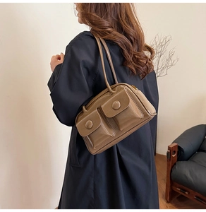 Detail of brown patent leather underarm bag with double front pockets and gold zippers