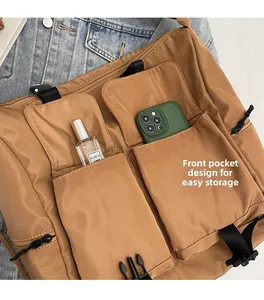 Close-up of khaki nylon tote bag featuring functional front pockets and buckle closure