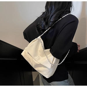 Detail of white patchwork chain shoulder bag with MICHTAM logo on model in minimalist setting
