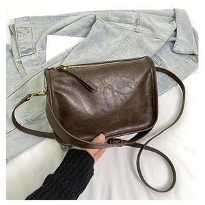 Détail du sac à bandoulière marron vintage avec cuir ciré et fermeture dorée
