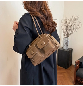 Detail of glossy brown faux leather shoulder bag with two front flap pockets and buckles