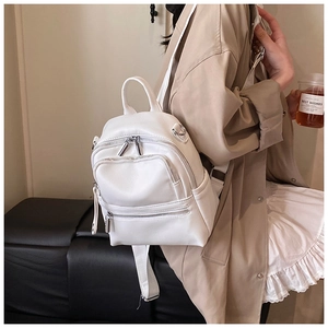 Side view of white textured faux leather backpack worn with elegant beige trench coat