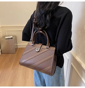 Dettaglio borsa in pelle marrone con strisce diagonali e fibbia a forma di ferro di cavallo
