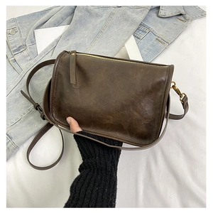 Détail de la texture en cuir marron foncé et de la fermeture éclair en métal du sac