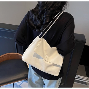 Detailed view of cream white tote bag with woven chain strap worn by a model