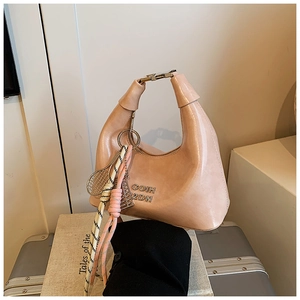 Sac croissant rose pâle avec breloque tennis sur une valise argentée brillante