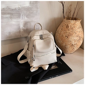 Detail of cream beige pebbled leather backpack with silver zippers and side pocket