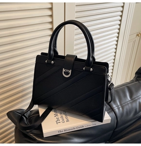 Dettaglio borsa tote in pelle nera con trama litchi e chiusura a ferro di cavallo