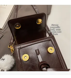 Detail view of strong magnetic buckles and vintage leather texture on brown crossbody bag