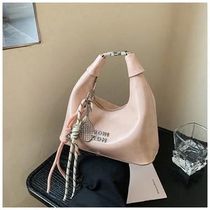 Vue détaillée du sac hobo en cuir rose avec nœuds tressés et breloque tennis