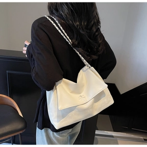 Close-up of minimalist white leather chain bag with silver logo on casual outfit