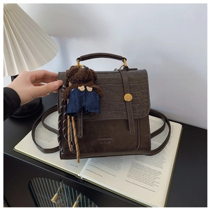 Close-up of vintage brown leather backpack with crocodile texture and cute bear charm