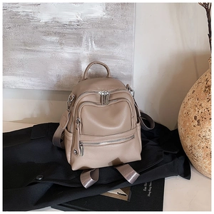 Detail of lychee pattern faux leather backpack with silver zippers and grey woven straps