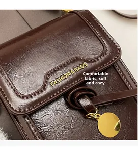 Detail of soft brown pebble leather texture and golden metal pendant on women crossbody bag