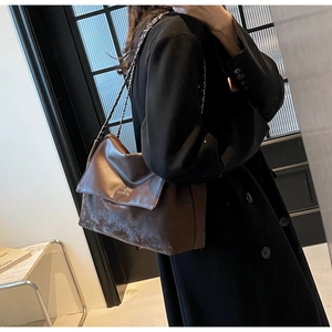 Detail of dark brown leather shoulder bag featuring silver chain strap and logo