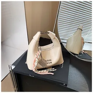 Détail du sac à main demi-lune crème avec fermoir métallique et pendentif en corde tressée