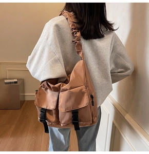 Detail of caramel nylon tote bag showing pleated shoulder straps and utility buckles