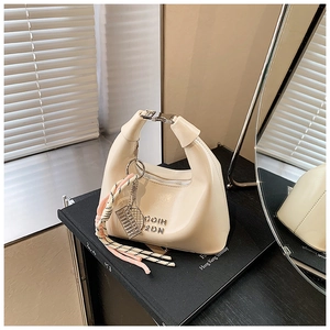 Détail du sac croissant crème avec boucle argentée et pendentifs en cordon colorés