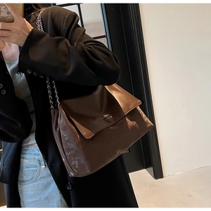 Close-up of vintage dark brown tote bag featuring metal chain strap and brand logo detail