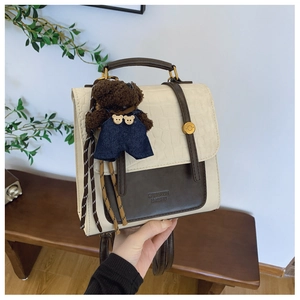 Detail of stylish color-block backpack with crocodile pattern and bear charm