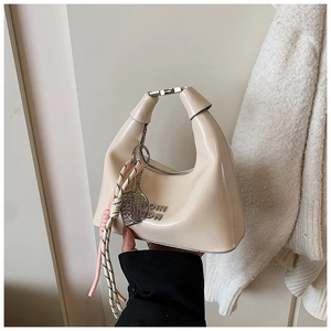 Détail du sac à main croissant crème avec poignée métallique et cordon décoratif